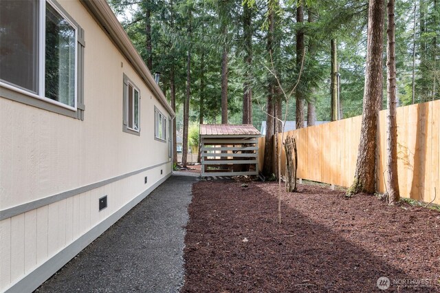 view of yard featuring an outbuilding, a storage shed, and fence