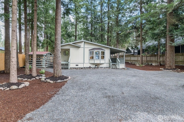 view of front of property featuring gravel driveway, fence, and crawl space