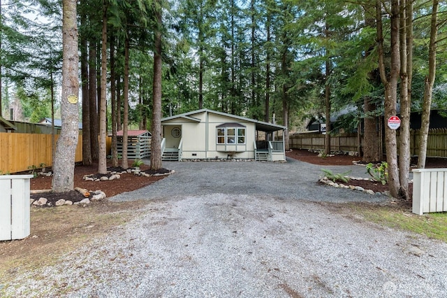 view of front of property featuring crawl space, driveway, and fence