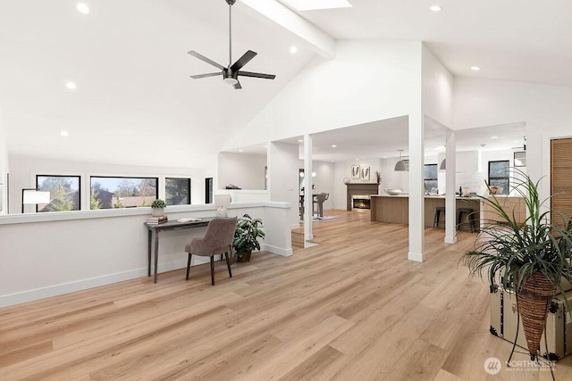 living area with wood finished floors, baseboards, high vaulted ceiling, a warm lit fireplace, and beamed ceiling