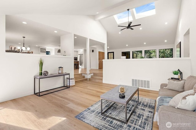 living room featuring visible vents, wood finished floors, high vaulted ceiling, and a skylight