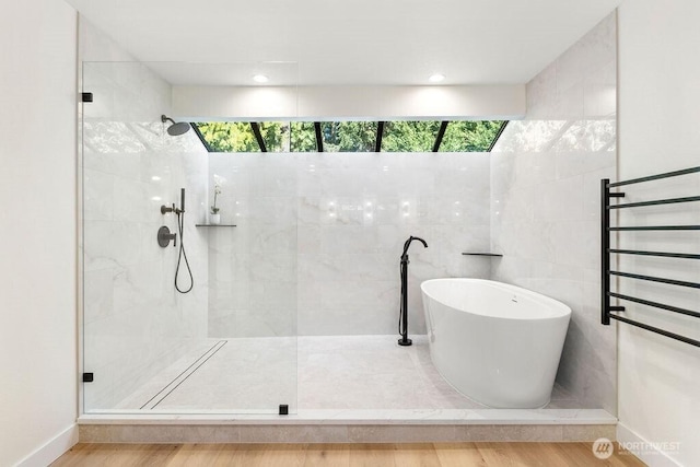 bathroom featuring baseboards, tiled shower, a soaking tub, and wood finished floors