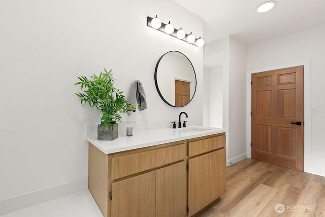 bathroom with vanity, wood finished floors, and baseboards