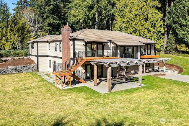 back of property with a tile roof, a patio, stairs, a yard, and a chimney