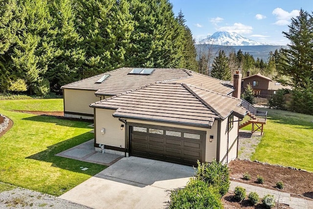 ranch-style home with a front yard, driveway, an attached garage, a tiled roof, and a mountain view