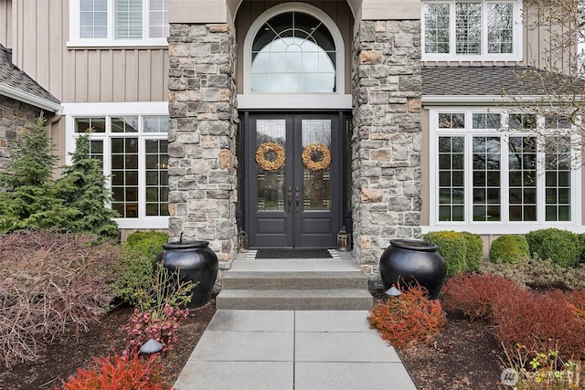 doorway to property featuring french doors, stone siding, and board and batten siding