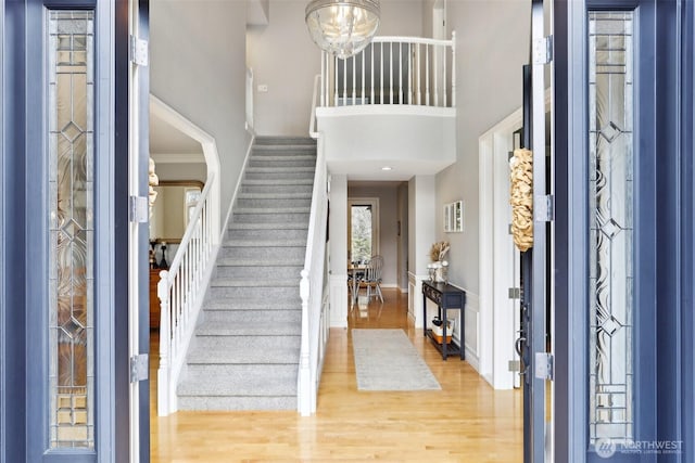 entrance foyer featuring stairway, ornamental molding, a towering ceiling, and wood finished floors