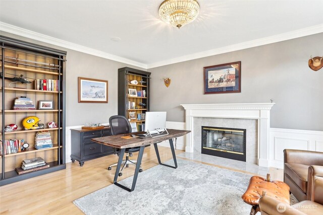 office area featuring a premium fireplace, light wood-style flooring, and ornamental molding