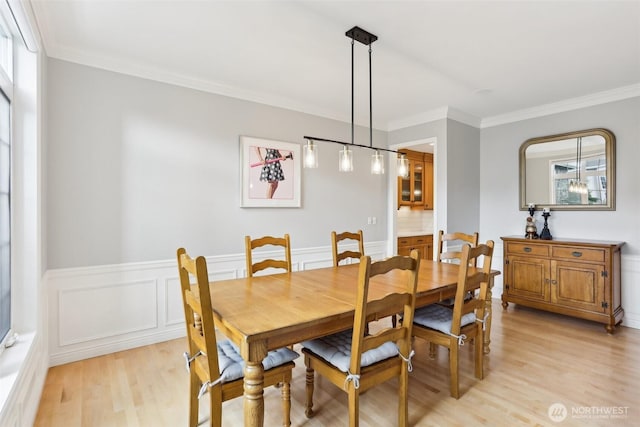 dining room featuring wainscoting, light wood-type flooring, and ornamental molding