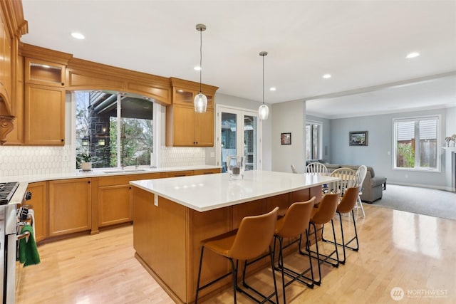 kitchen featuring a kitchen island, glass insert cabinets, open floor plan, light countertops, and decorative backsplash