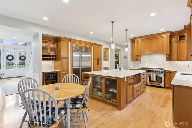 kitchen with a warming drawer, a sink, brown cabinetry, light countertops, and high end appliances