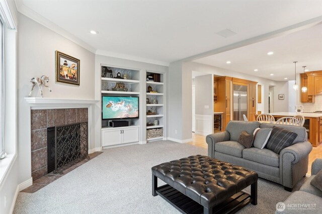 living area featuring a fireplace, built in shelves, light colored carpet, and recessed lighting