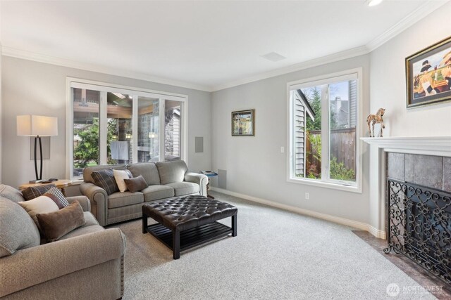 carpeted living room featuring a tiled fireplace, baseboards, and ornamental molding