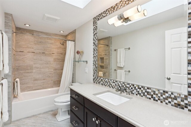 bathroom featuring backsplash, vanity, toilet, and shower / tub combo