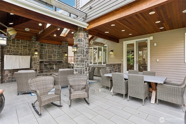 view of patio with outdoor dining area, french doors, and an outdoor stone fireplace