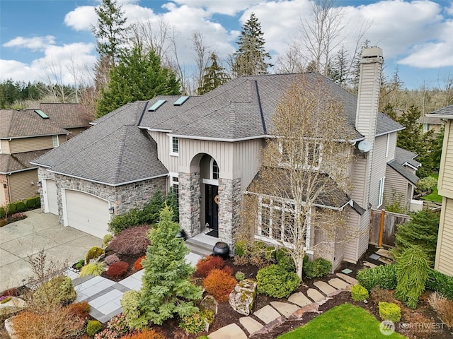 view of front of property featuring driveway, an attached garage, a chimney, a shingled roof, and stone siding