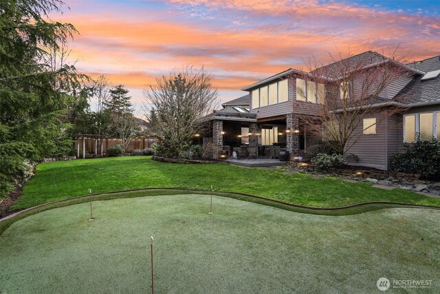 yard at dusk featuring a patio and fence