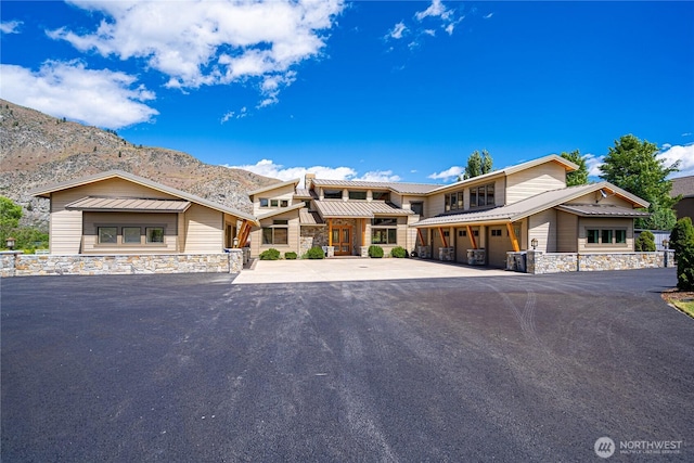 view of front of property with metal roof, stone siding, a mountain view, and an attached garage