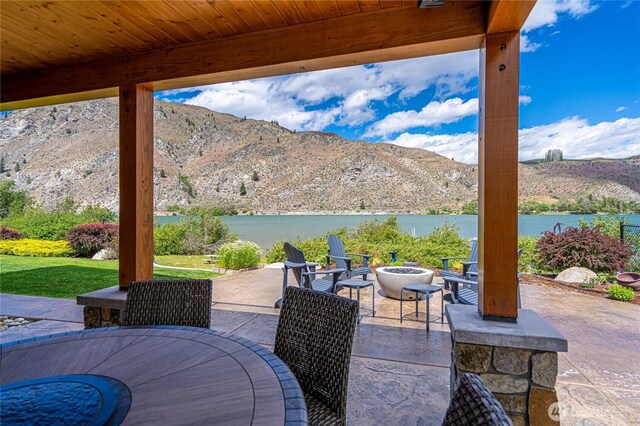 view of patio featuring a fire pit, outdoor dining area, and a water and mountain view
