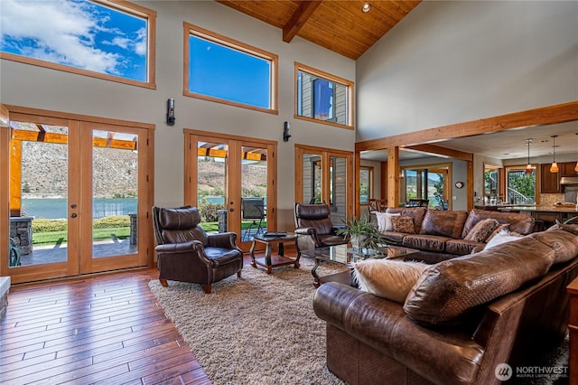living area featuring french doors, beamed ceiling, high vaulted ceiling, wood-type flooring, and wood ceiling