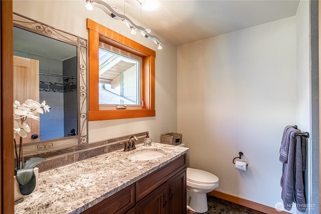 full bath featuring toilet, vanity, and baseboards