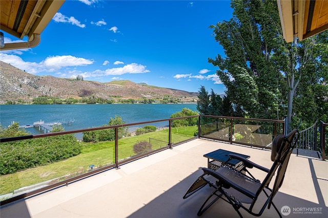 view of patio / terrace featuring a water and mountain view and a balcony