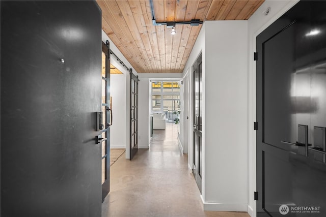 corridor with a barn door, finished concrete floors, baseboards, and wooden ceiling