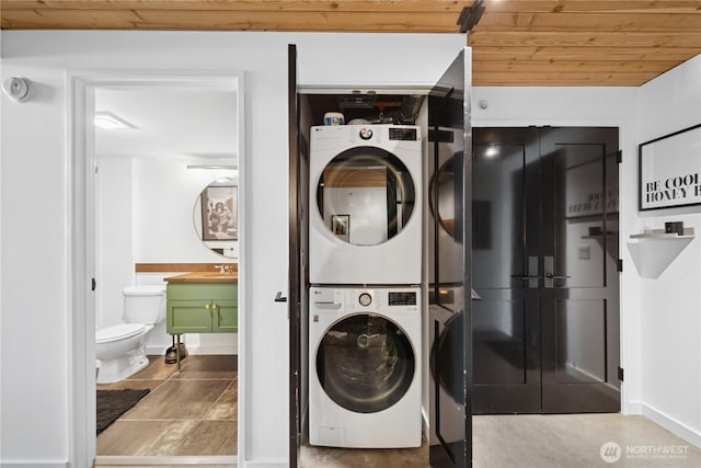 washroom featuring a sink, stacked washer and dryer, wood ceiling, and laundry area