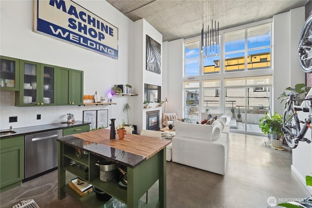 kitchen with butcher block countertops, stainless steel dishwasher, a high ceiling, concrete floors, and green cabinetry