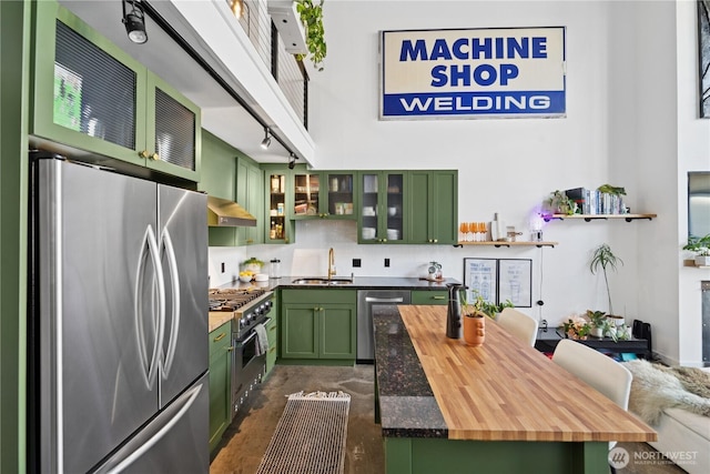 kitchen featuring green cabinets, extractor fan, butcher block counters, stainless steel appliances, and a sink