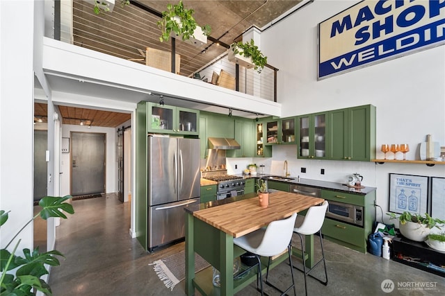 kitchen with green cabinetry, stainless steel appliances, a high ceiling, and finished concrete floors