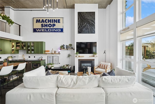 living room with a glass covered fireplace and a towering ceiling