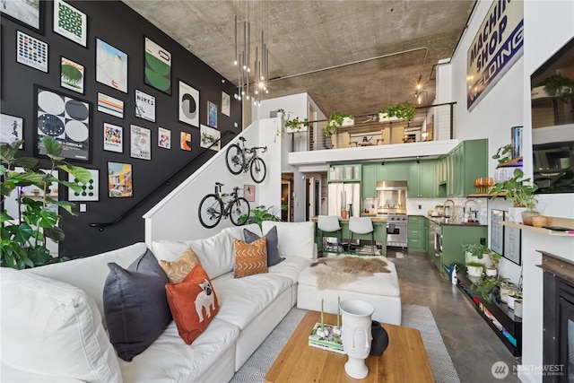 living room featuring finished concrete floors, stairs, and a towering ceiling