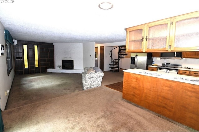 kitchen with open floor plan, light countertops, brown cabinets, appliances with stainless steel finishes, and a fireplace