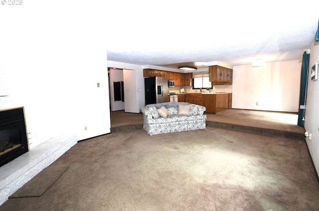 unfurnished living room featuring a fireplace, baseboards, carpet floors, and a sink