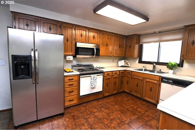 kitchen with a sink, stainless steel appliances, brown cabinets, and light countertops