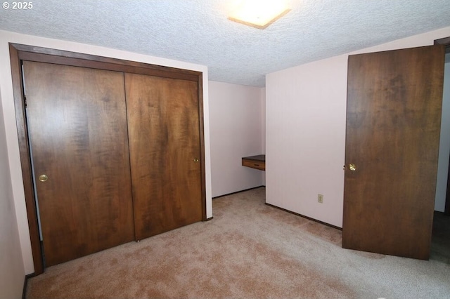 unfurnished bedroom featuring light colored carpet, a closet, and a textured ceiling