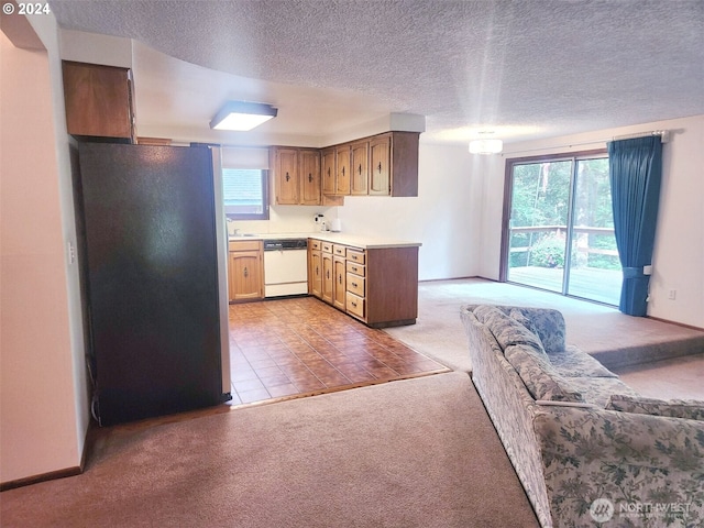 kitchen with white dishwasher, freestanding refrigerator, light countertops, a textured ceiling, and light colored carpet