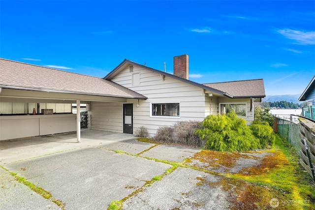 back of house with a patio, a shingled roof, a chimney, and fence