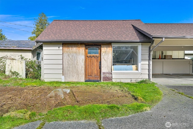 view of front facade with stone siding, fence, and a shingled roof