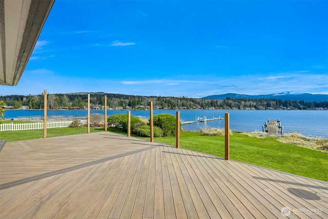 view of dock featuring a lawn, fence, and a water view