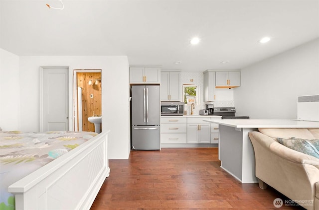 kitchen featuring dark wood-type flooring, light countertops, recessed lighting, stainless steel appliances, and white cabinetry