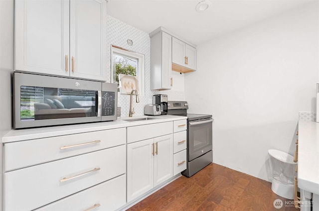 kitchen featuring light countertops, dark wood-style flooring, appliances with stainless steel finishes, and a sink