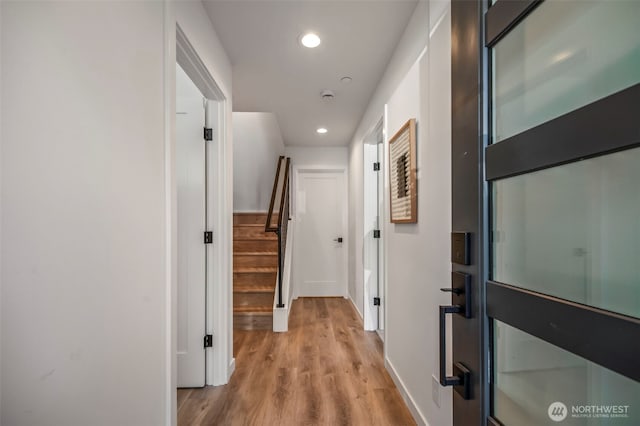 corridor with stairway, recessed lighting, baseboards, and wood finished floors