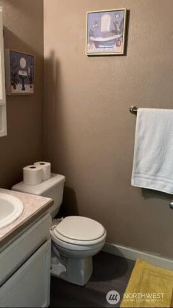 bathroom featuring baseboards, toilet, and vanity