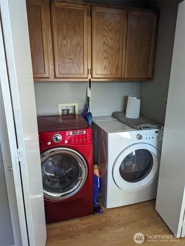 washroom with light wood-type flooring, cabinet space, and washing machine and clothes dryer