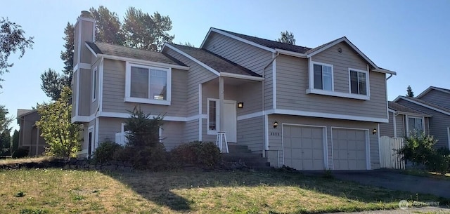 raised ranch with a front lawn, a garage, driveway, and a chimney