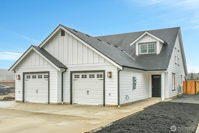 view of front facade featuring fence, driveway, an attached garage, a shingled roof, and board and batten siding