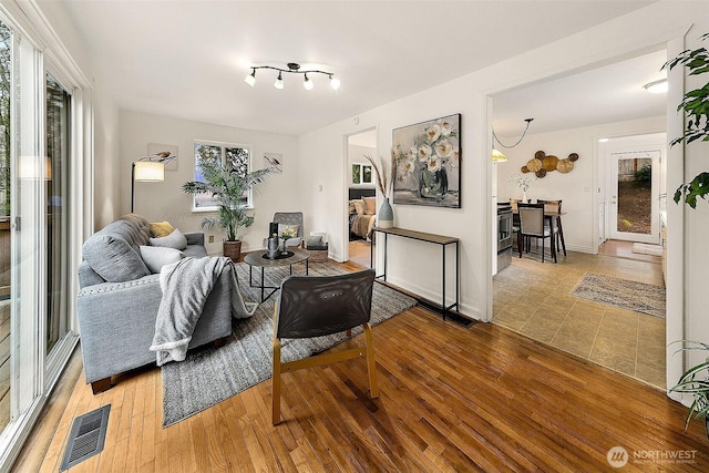 living room with visible vents, baseboards, and hardwood / wood-style flooring