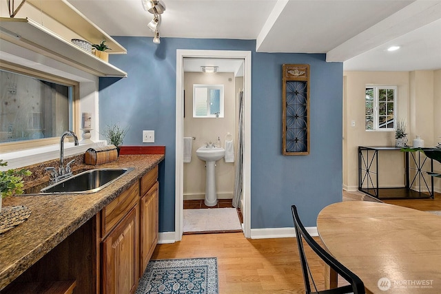 bathroom with rail lighting, wood finished floors, baseboards, and a sink